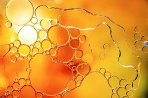 Bright yellow and orange colorful bubbles on water surface in abstract background photo