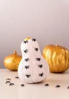 White and gold halloween spooky pumpkins with spiders crawling on white table