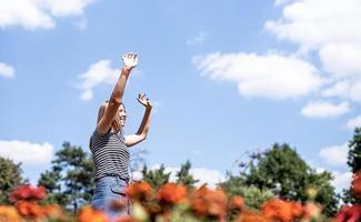 Mujer riendo feliz en un día soleado en la naturaleza en verano con los brazos arriba