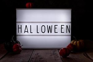 Halloween light box in the dark room with pumpkins on wooden floor photo