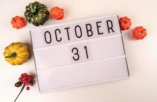 October 31 light box on white table with pumpkins scattered around photo