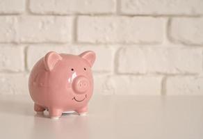 pink piggy bank on white brick wall background photo