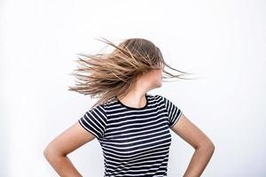 Hermosa mujer sonriente en ropa casual divirtiéndose girando sobre fondo de pared blanca foto