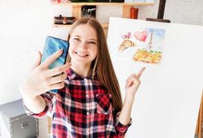 Young woman artist taking a selfie with her picture photo