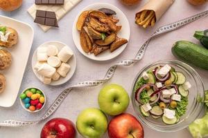 Fruit and vegetables vs sweets and potato fries top view flat lay photo