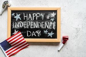 Closeup of American flag with a chalkboard with text Happy Independence Day top view photo