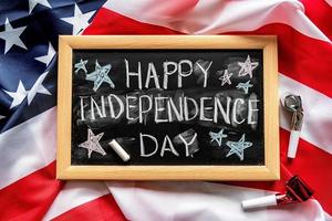 Closeup of American flag with a chalkboard with text Happy Independence Day top view photo