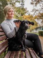 Mujer joven abrazando a su perro cocker spaniel en el banco en el parque foto