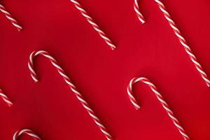 candy canes pattern top view on bright red background photo