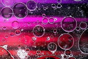 Pink and purple abstract pattern made with oil bubbles on water coming up in motion photo