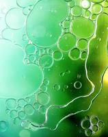 Bright green colorful bubbles on water surface in abstract background