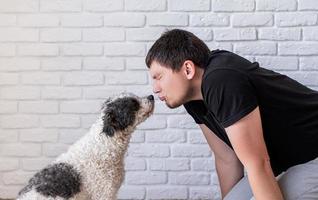 Young funny man kissing his bichon frise dog photo