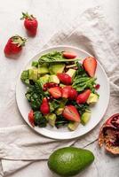 salad with spinach, avocado and strawberries on white background top view flat lay photo