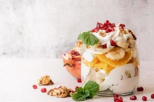 fruit salad with pomegranate, walnuts and fresh fruits in a jar on rustic concrete background front view photo