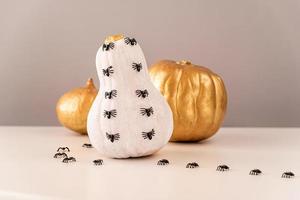 White and gold halloween spooky pumpkins with spiders crawling on white table photo