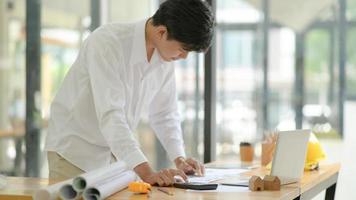 Architects use calculator to design and plan building construction for clients. photo