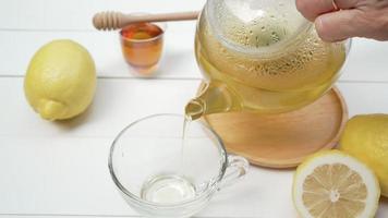 varmt grönt te med citron och honung hälldes i tekopp serveras på bordet i caféet video
