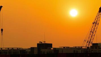 time-lapse 4k kranen die containers optillen met zonsondergang op de achtergrond in de avond. video