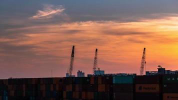 Time-lapse 4K Cranes lifting containers background sunset in the evening.
