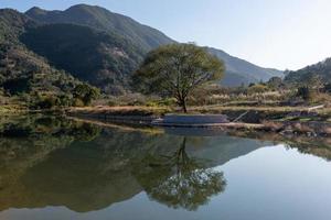 el río rural refleja la montaña, y las aldeas y los bosques están bajo el cielo azul foto