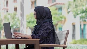 mujeres musulmanas sentadas afuera trabajando de acuerdo con el lema trabajo desde casa ella estaba trabajando en una residencia privada.