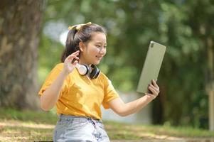 Asian teen girl greets her friends with a tablet. photo