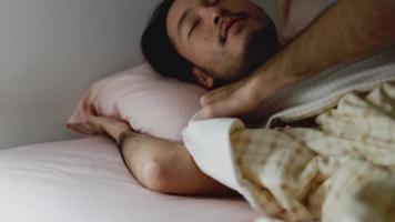 homme asiatique endormi faisant de beaux rêves dans la chambre à coucher à la maison. video