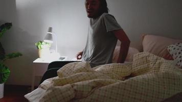 homem asiático apaga a luz antes de dormir no quarto em casa. video
