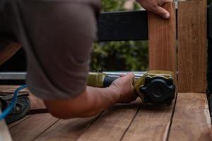 Hand man carpenter using air nail gun to complete wood table in garden photo