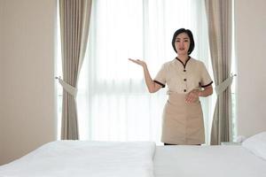 Asia joven camarera en la habitación del hotel su lool a la cámara foto