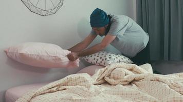 Hombre asiático arregla cojines en el dormitorio antes de salir. video