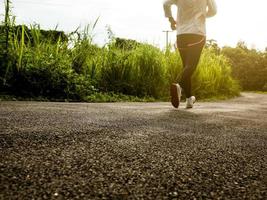 corredoras que se ejecutan en el camino en el entrenamiento matutino para maratón y fitness. concepto de estilo de vida saludable. atleta corriendo haciendo ejercicio al aire libre. piernas de primer plano. foto