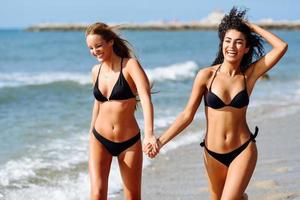 Two young women with beautiful bodies in swimwear on a tropical beach photo