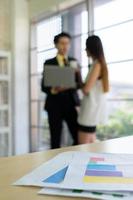 young asian woman using computer to consult project with businessman near window in woking office photo