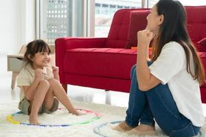 joven asiático jugando juego con su madre en la sala de estar en casa. concepto de familia unida foto