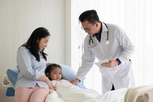 médico asiático visita a la niña y la madre que está enferma e ingresada en la sala de pediatría del hospital. concepto de salud y medicina foto