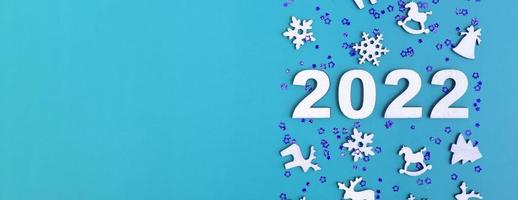 Wooden numbers for new year 2022 with stars and christmas decor on blue background with copy space. Banner format photo