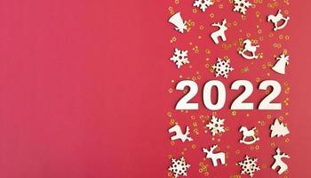 Wooden numbers for new year 2022 with stars and christmas decor on red background with copy space. Banner format photo