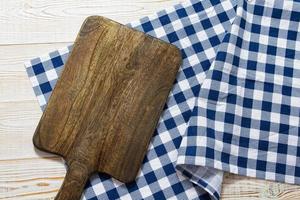 Close up of cutting board with chekered tablecloth on wooden background. photo