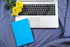 Blue notepad mock up on laptop and yellow flowers background close up photo