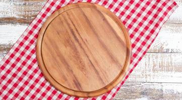 empty pizza board on empty wooden table with tablecloth,napkin - top view photo
