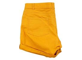 Pantalones cortos naranjas doblados en el fondo de la maqueta de aislamiento - ropa de moda de verano foto