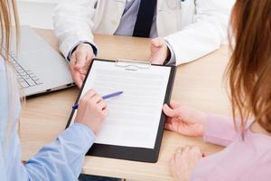 Doctor with patients in medical office sign a contract. Healthcare concept. Medical insurance. photo