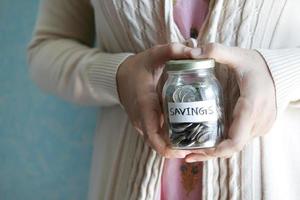 women hand hold a saving coins jar photo