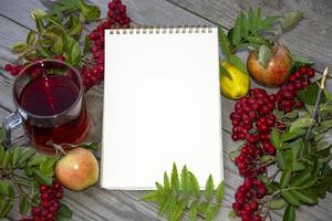 Notepad with a white margin for text. Template with a white sheet of paper. Rowan berries and apples on a wooden background. photo