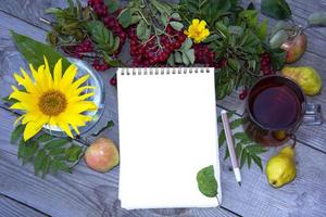 Notepad with a blank sheet of paper for writing. Template with a field for text. Natural background from berries, flowers and a drink. photo