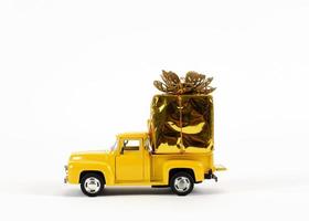 Juguetes de coche amarillo con caja de regalo dorada para decoración navideña sobre fondos blancos foto