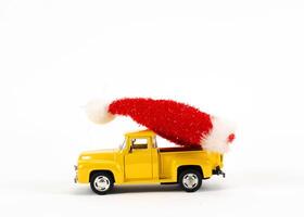 Juguetes de coche amarillo con decoración de sombrero de navidad sobre fondos blancos foto