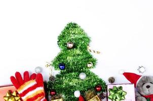 Árbol de Navidad con decoración de osito y guantes rojos sobre fondos blancos arriba foto