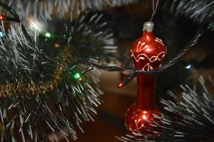 árbol de navidad con juguetes y guirnaldas luminosas en casa y en el fondo de la oficina foto